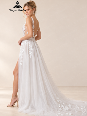 Side view of an ivory lace-applique wedding dress with an open back, front split, and floor-length tulle skirt.