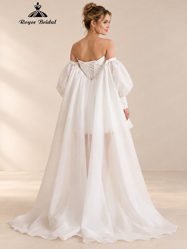 Back view of an ivory mini wedding dress with detachable sleeves, covered buttons, and sheer train.